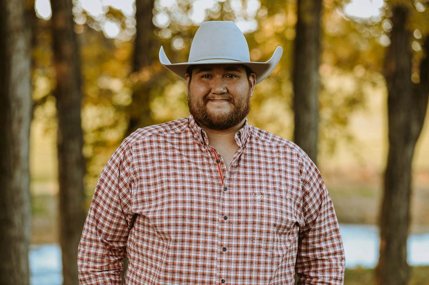 Austin Neahring wearing a white cowboy hat and a red, plaid buttoned up shirt