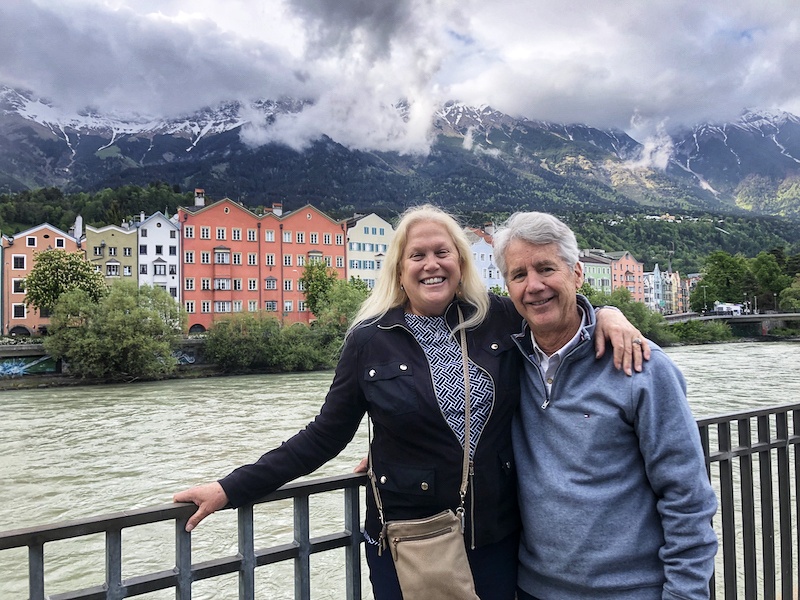 Steve Wickes and his significant other smiling for a photo with a scenic view of the mountains in the background