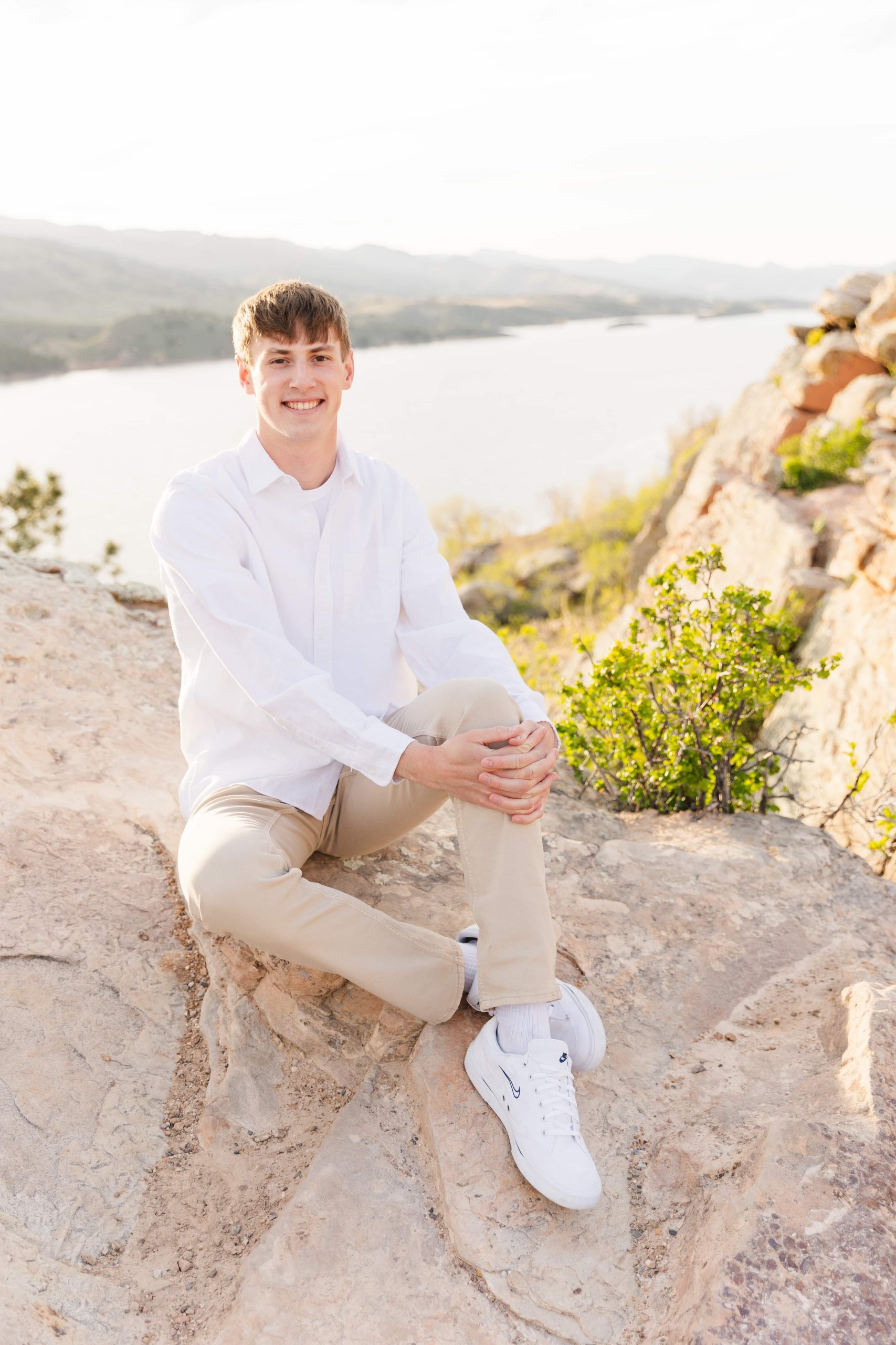 Justice Rees from Flat River Minerals, sitting on top of a rock with a scenic lake view in the background